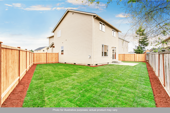 a backyard with a white house and a wooden fence